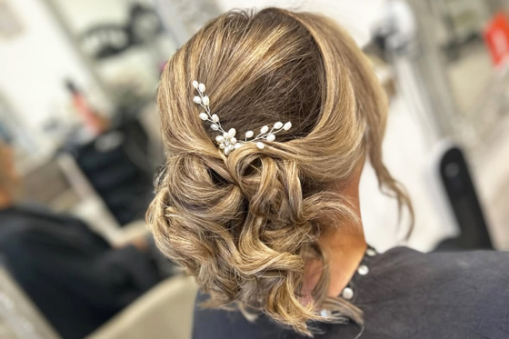 Updo with white flower-inspired hair accessory on girl